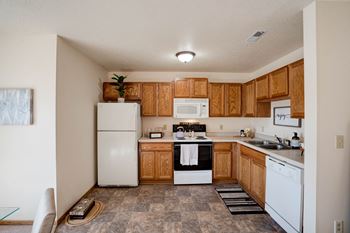Spacious Kitchen With Tile-Style Flooring, Oak Cabinets & White Appliances